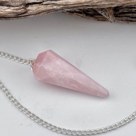 Pink crystal pendulum on a silver chain with a natural background