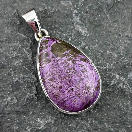 Purple teardrop pendant on a gray stone background